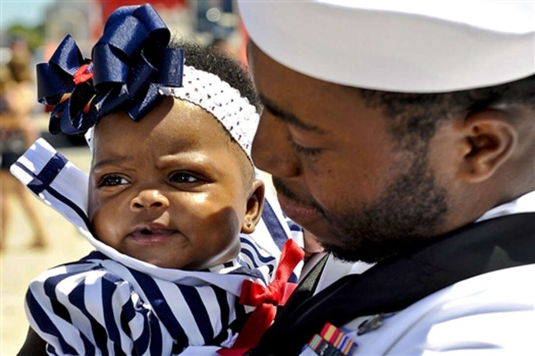 Navy Seaman Marico Dean holds his daughter for the first time as he returns on the attack submarine USS Norfolk in Norfolk, Va., Aug. 26, 2014. The submarine, which arrived at its home port on Naval Station Norfolk after completing its final deployment, will begin the inactivation process in 2015. 