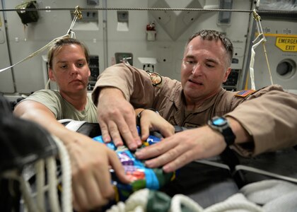Master Sgts. Stephen Brown (right) and Emily Edmunds, 816th Expeditionary Airlift Squadron loadmasters,  attach candy to container delivery system bundles filled with fresh drinking water on a C-17 Globemaster III in preparation for a humanitarian airdrop over the area if Amirli, Iraq Aug. 30, 2014. The candy was collected by the squadron to supplement United States government humanitarian aid. (U.S. Air Force photo by Staff Sgt. Shawn Nickel)