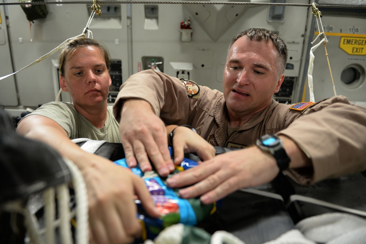 U.S. Air Force Master Sgts. Stephen Brown and Emily Edmunds attach candy to container delivery system bundles filled with fresh drinking water on a C-17 Globemaster III in preparation for a humanitarian airdrop over the area of Amirli, Iraq, Aug. 30, 2014. The candy was collected by the squadron to supplement United States’ humanitarian aid. Brown and Edmunds, loadmasters, are assigned to the 816th Expeditionary Airlift Squadron. U.S. Air Force photo by Staff Sgt. Shawn Nickel