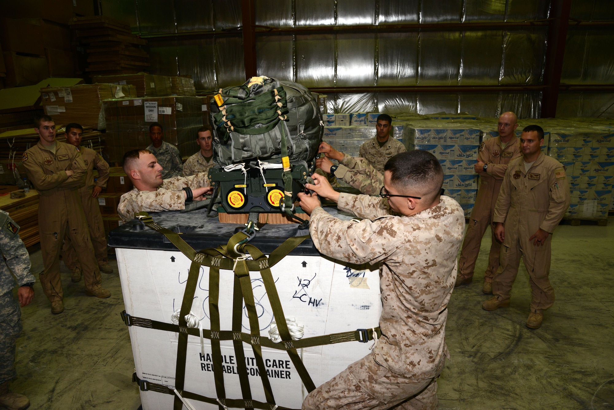 SOUTHWEST ASIA - Joint service members demonstrate attaching a Joint Precision Airdrop System bundle to a pallet during training here Nov. 25, 2014. The JPADS refresher training ensured the parachute riggers are up-to-date on the current system and procedures. (U.S. Air Force photo by Tech. Sgt. Jared Marquis/released)