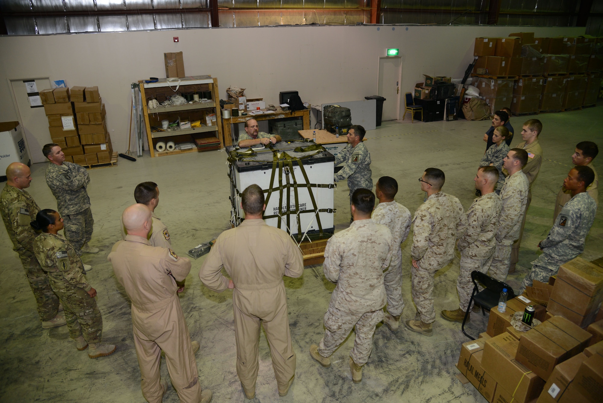 SOUTHWEST ASIA - Joint service members listen as Tom Meador, Joint Precision Airdrop System trainer, explains how to attach a bundle to a pallet during training here Nov. 25, 2014. The JPADS refresher training ensured the parachute riggers are up-to-date on the current system and procedures. (U.S. Air Force photo by Tech. Sgt. Jared Marquis/released)