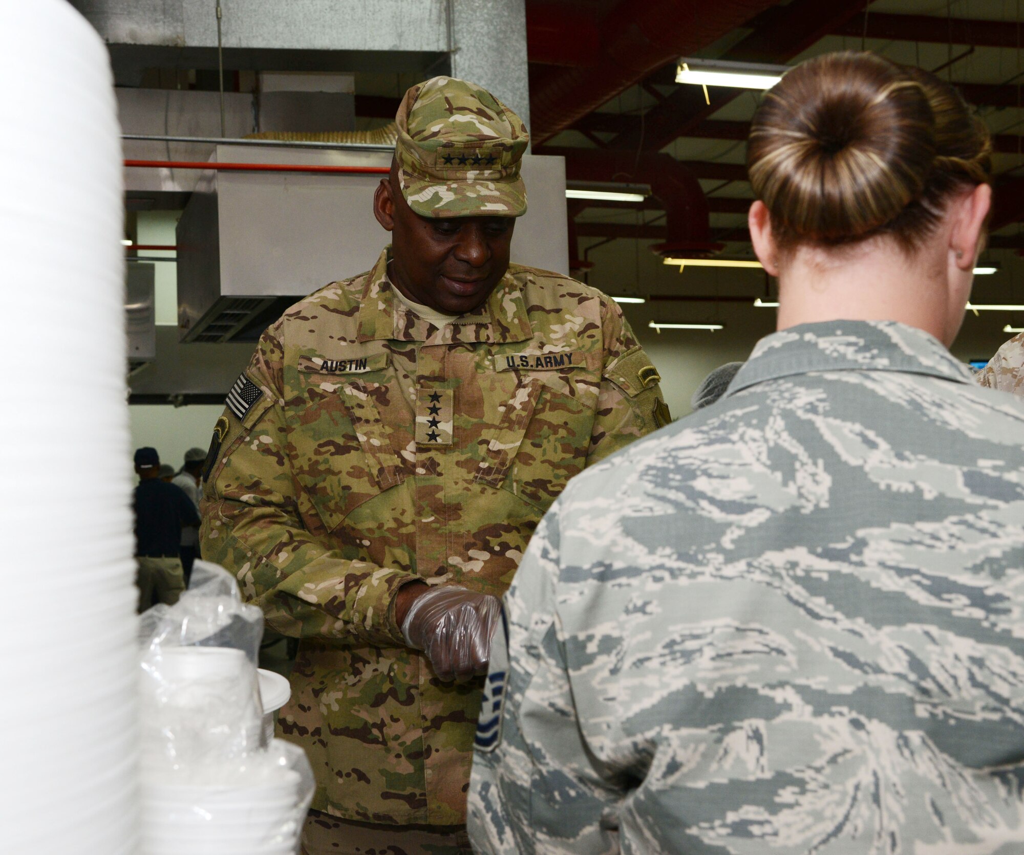 SOUTHWEST ASIA - U.S. Army Gen. Lloyd J. Austin III, U.S. Central Command commander, puts on gloves as he prepares to serve Thanksgiving meals to joint and coalition service members here Nov. 27. Austin spent the day serving meals and talking to service members. (U.S. Air Force photo by Tech. Sgt. Jared Marquis/released)