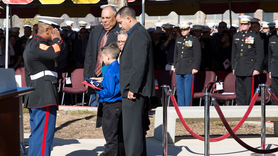 First Sgt. Alvoid Hamilton, first sergeant for 1st MSOB, presents a folded American Flag to the family of Staff Sgt. Christopher Diaz a Military Working Dog handler who was killed in action, Sept. 28, 2011, during a Navy Cross and Bronze Star awards ceremony aboard Camp Pendleton, Calif., Nov. 25, 2014.  (U.S. Marine Corps Photo by Sgt. Scott A. Achtemeier / Released)