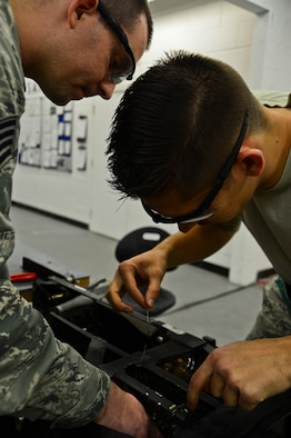 Staff Sgt. Kevin Mayo and Senior Airman Benjamin Roberds complete a mortar disconnect assembly installation on an ejection seat Nov. 19, 2014, at Royal Air Force Lakenheath, England. An Air Force Smart Operations for the 21st Century event was held to streamline operations and reduce wasted materials and manpower. Mayo is a 48th Component Maintenance Squadron aircrew egress systems craftsman and  Roberds is a 48th CMS aircrew egress systems journeyman. (U.S. Air Force photo/Airman 1st Class Erin R. Babis)