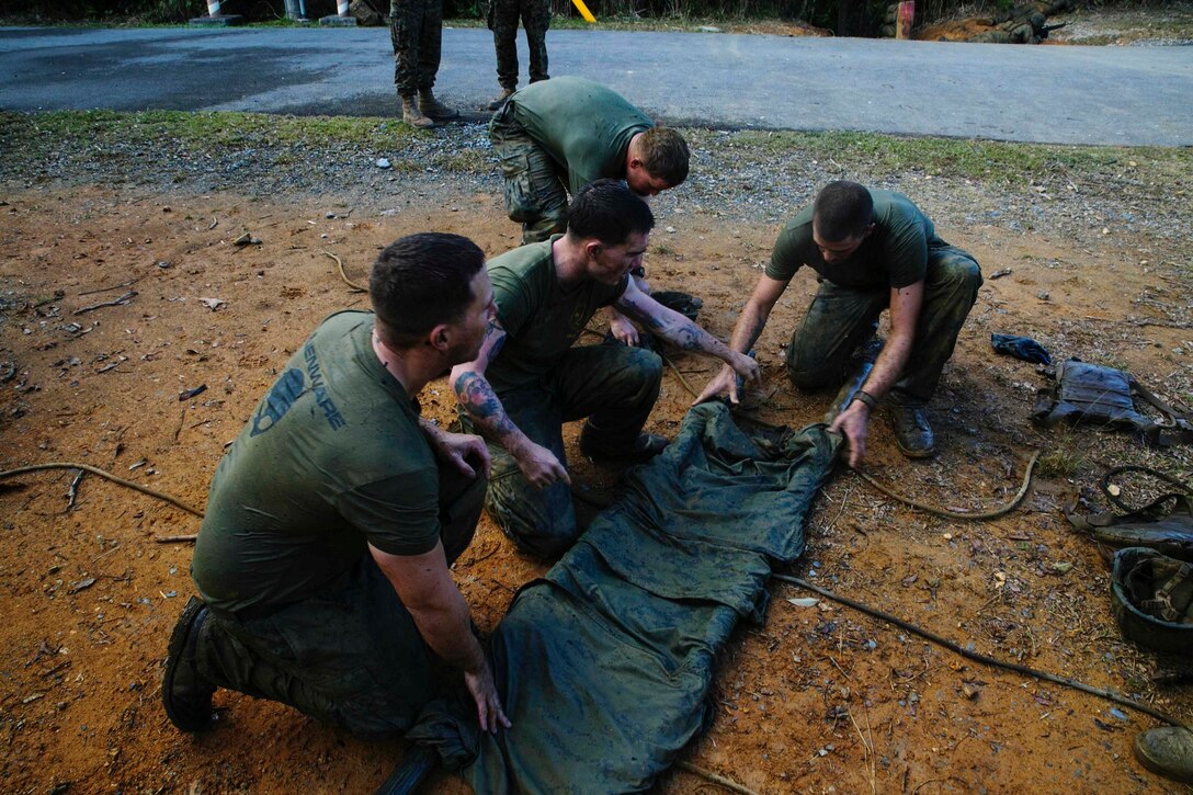 Marines make an improvised litter using sticks they found and their blouses during the endurance course Nov. 25 at the Jungle Warfare Training Center on Camp Gonsalves. The endurance course is a four-mile course that includes rappelling, rope bridges, water obstacles and a simulated casualty station. The Marines are with 1st Battalion, 1st Marine Regiment, currently assigned to 4th Marine Regiment, 3rd Marine Division, III Marine Expeditionary Force, under the unit deployment program. 