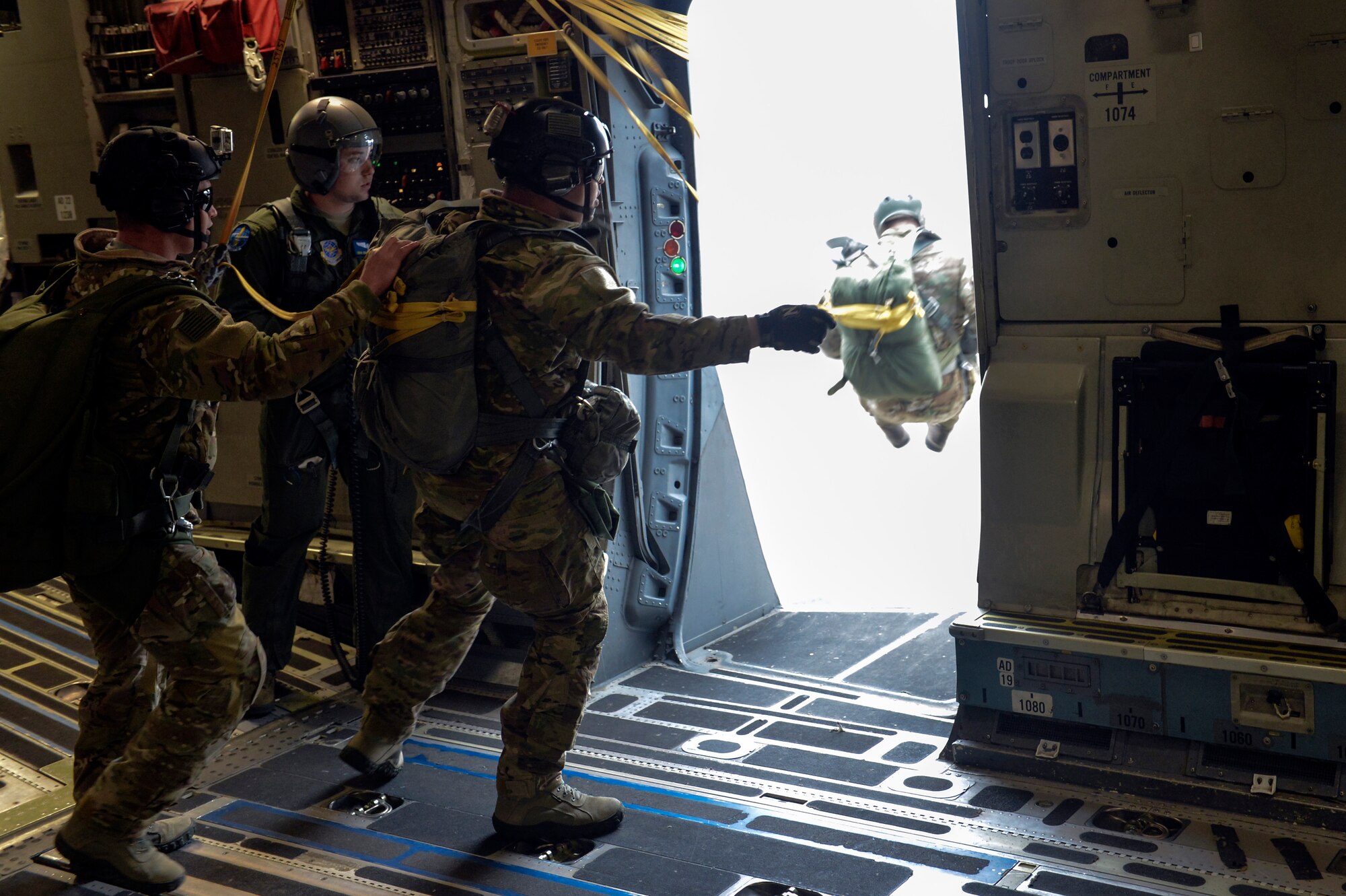 Staff Sgt. Raymond Caballero-Perez (center), 22nd Training Squadron parachuting shop NCO in charge, watches as one of his Airmen jump from a McChord Field C-17 Globemaster III during static line jump training Nov. 24, 2014, at Fairchild Air Force Base, Wash. Caballero-Perez guided his first group of 12 Airmen as they jumped from the C-17 at 1,000 feet for their static line jump before the second pass where another 12 Airmen, including himself, jumped from the aircraft. (U.S. Air Force photo/Staff Sgt. Russ Jackson)