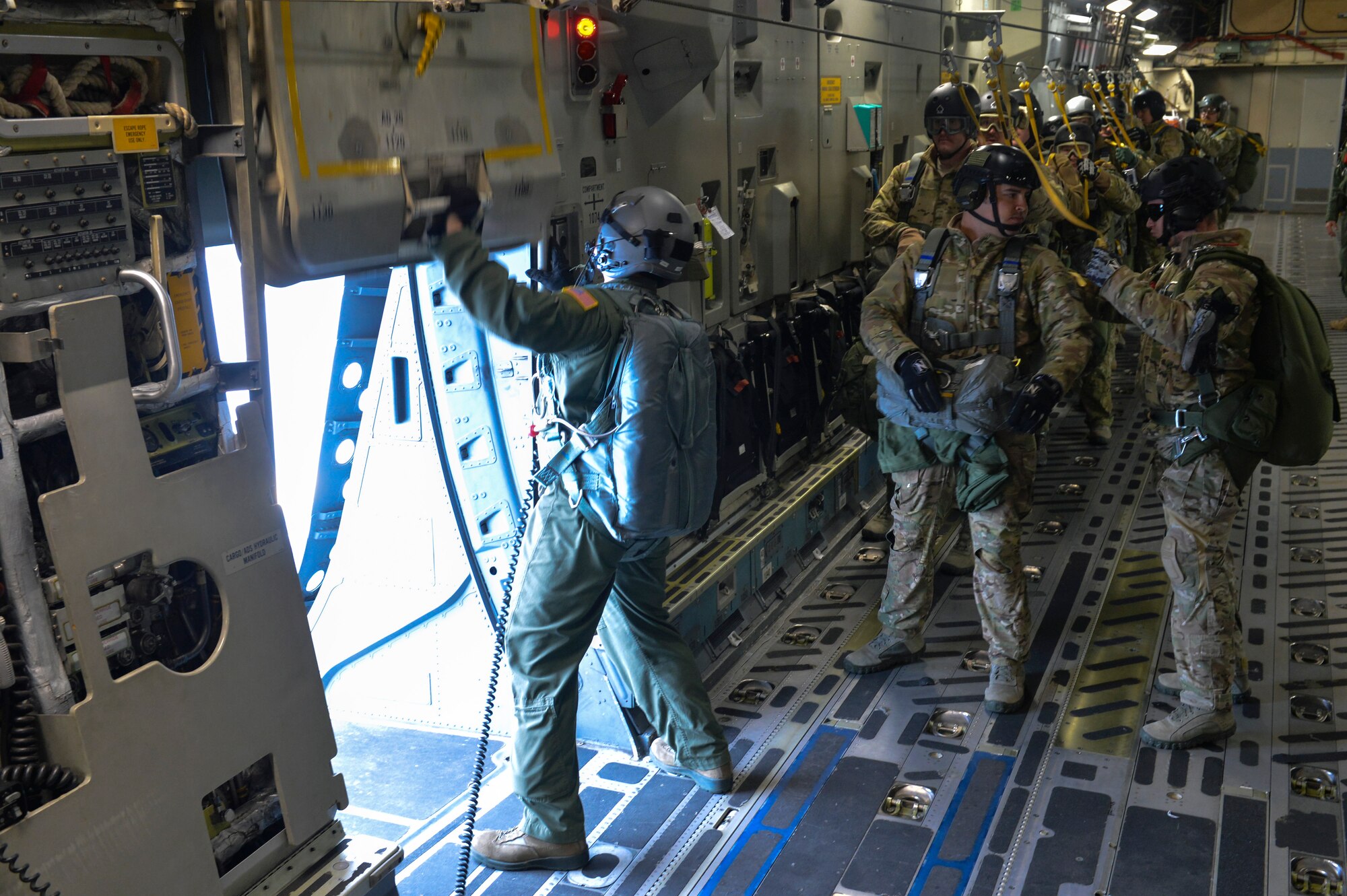 Senior Airman Brock Wranik, 7th Airlift Squadron loadmaster, opens the side door of a McChord Field C-17 Globemaster III as Airmen from Fairchild Air Force Base’s 22nd Training Squadron prepare for static line jump training Nov. 24, 2014, at Fairchild AFB, Wash. Brock made sure to give Airmen from the 22nd TRS countdown times at 10 minutes, six minutes, two minutes, one minute, 30 seconds and the final 10 seconds before jumping from the jet. (U.S. Air Force photo/Staff Sgt. Russ Jackson)