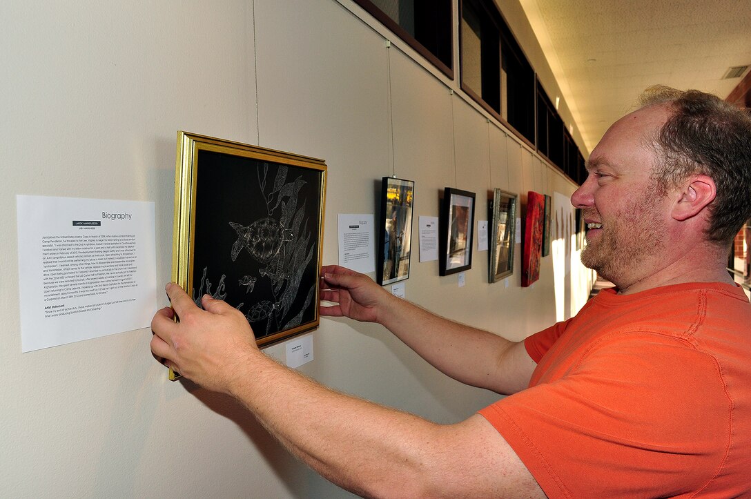 Troy Muller, an art and history teacher at Metropolitan Community College in Omaha places a descriptive name tag beneath a piece of art at the Fort Omaha Campus of Metro. This art illustrates the actual pieces of shrapnel pulled from body of Phillip Schladweiler after being wounded in Ramadi, Iraq in 2006. The 2014 Metro Military and Veteran Juried Art Exhibition at Metropolitan Community College’s Fort Omaha Campus, can be seen Monday through Thursday from 8 a.m. to 7 p.m. and Saturday from 8 a.m. to 5 p.m. The exhibition will run through Dec. 6. All proceeds go to a veteran artist and student artist scholarship funds. (U.S. Air Force photo by D.P. Heard/Released)