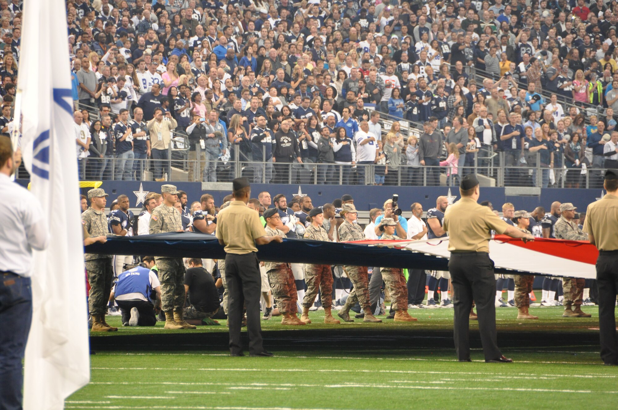 NAVAL AIR STATION FORT WORTH JOINT RESERVE BASE, Texas - Approximately 75 servicemembers hold the American flag on the field during the playing of the National Anthem at the Dallas Cowboys' Thanksgiving game Nov. 27, 2014. (U.S. Air Force photo/Capt. Candice Allen)