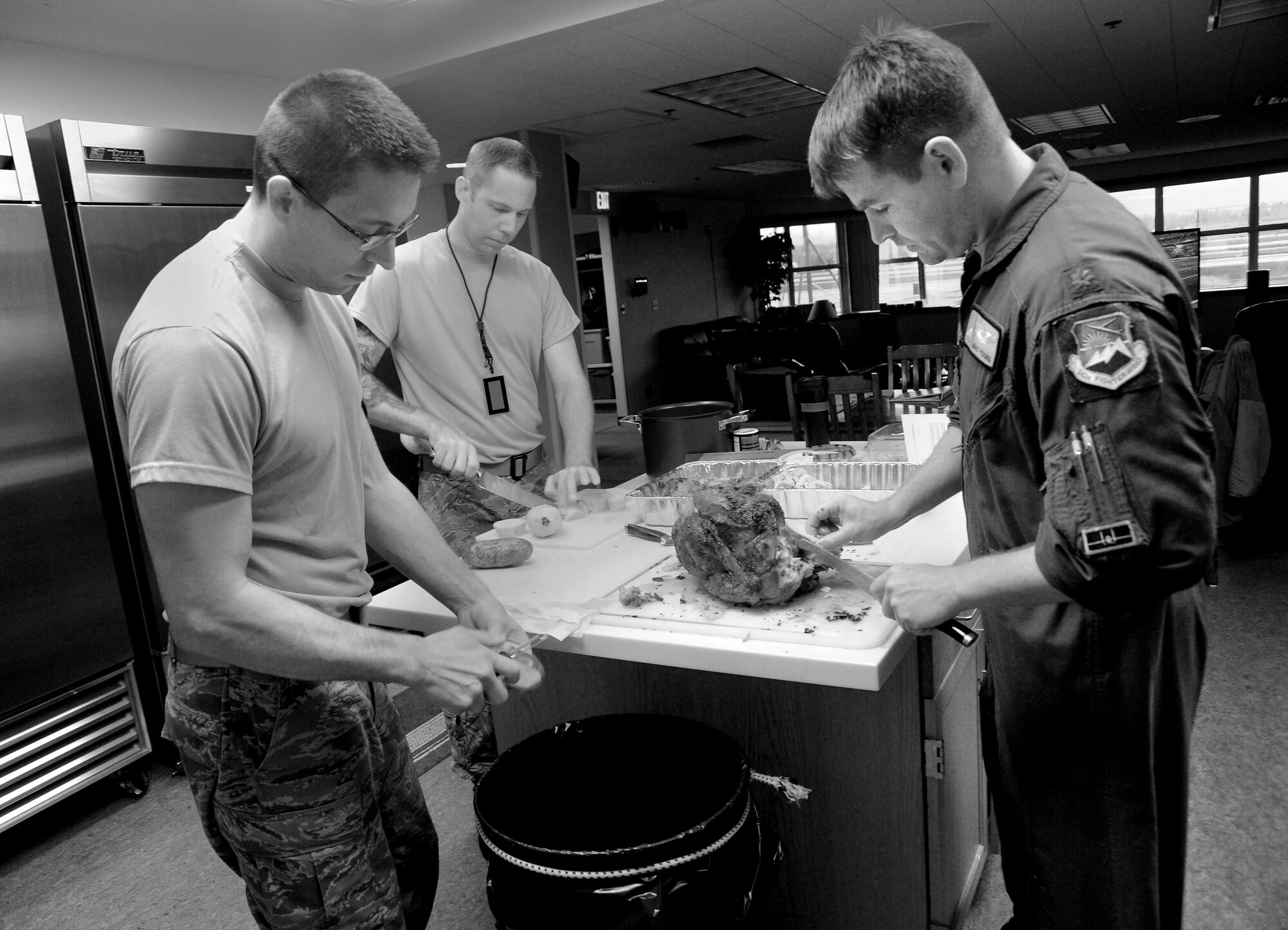 Oregon Air National Guard Maj. Bradley Young, a pilot assigned to the 123rd Fighter Squadron, 142nd Fighter Wing, Portland Air National Guard Base, Ore., cuts a Thanksgiving Turkey at the Alert Facility, as Staff Sgt. Matthew Shelburne, left, and Staff Sgt. Kyle Adair, center, prepare potatoes for dinner, Nov. 27, 2014. (U.S. Air National Guard photo by Tech. Sgt. John Hughel, 142nd Fighter Wing Public Affairs/Released)