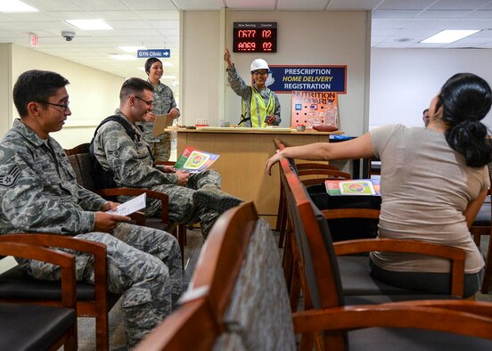 U.S. Air Force Senior Airman Catherine Scholar, 59th Medical Diagnostics and Therapeutics Squadron diet therapy journeyman, congratulates Airmen for answering correctly during a nutrition jeopardy game recently at the Wilford Hall Ambulatory Surgical Center, Joint Base San Antonio-Lackland, Texas. The event helped patients pass the time while waiting for their prescriptions, and provided them with nutritional information on foods we eat every day. (U.S. Air Force photo/Staff Sgt. Kevin Iinuma)