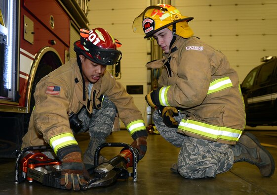 U.S. Air Force Staff Sgt. Minh Thlang, left, 100th Civil Engineer Squadron Fire Protection crew chief from Seattle, demonstrates to U.S. Air Force Airman 1st Class Jamie Perigny, 100th CES firefighter from Mathews, Va., how to operate the jaws of life Nov. 25, 2014, on RAF Mildenhall, England. Thlang earned the Square D Spotlight for exhibiting the Air Force Core Value of Excellence in All We Do. (U.S. Air Force photo by Airman 1st Class Jonathan Light/Released) 
