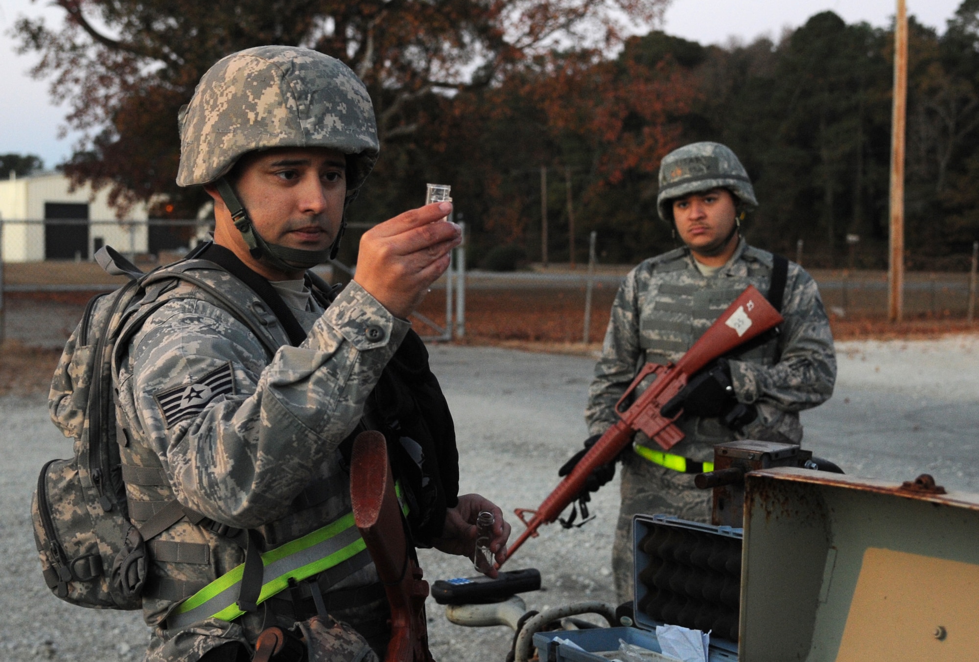 Tech. Sgt. Eddy Redondo, 4th Civil Engineer Squadron water and fuels maintenance technician, observes  a water sample while Airman 1st Class Manuel Acuña, 4th CES heavy equipment technician, provides escort during exercise Coronet Warrior 14-03 at Seymour Johnson Air Force Base, North Carolina, Nov. 20, 2014. Redondo tested the pH balance and chlorine levels of the water in the base’s simulated deployed area water tank. (U.S. Air Force photo/Senior Airman Ashley J. Thum)