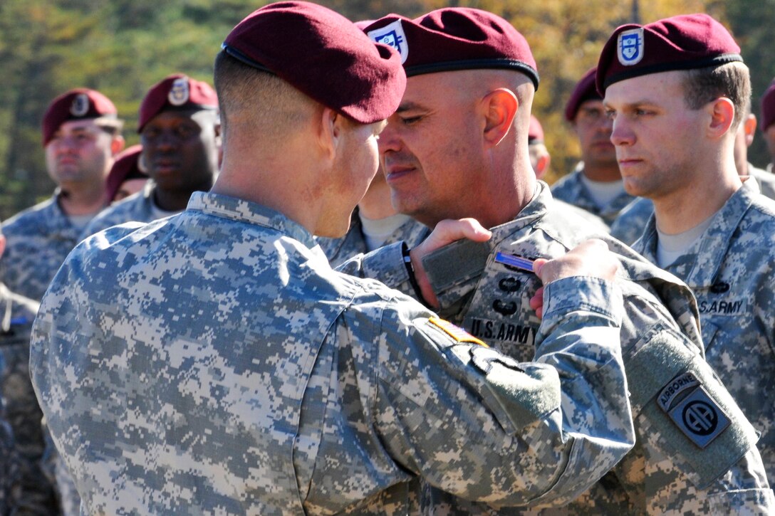 Army Col. Joseph A. Ryan, foreground, commander, 82nd Airborne Division's 2nd Brigade Combat Team, awards the Expert Infantryman Badge to a paratrooper after completing the testing on Fort Bragg, N.C., Nov. 21, 2014.