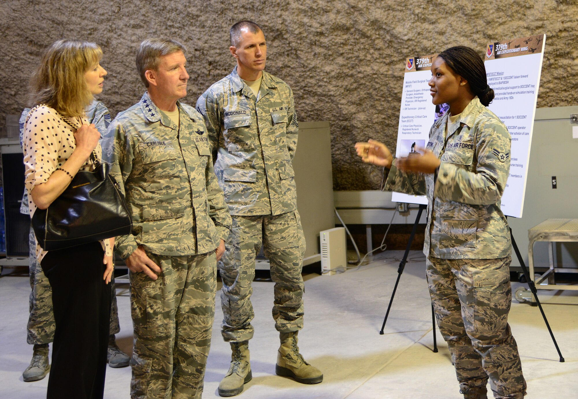U.S. Air Force Airman 1st Class Jolonda Houston, right, 379th Expeditionary Medical Support Squadron, briefs Gen.  Hawk Carlisle, commander of Air Combat Command, his wife Gillian and Chief Master Sgt. Steve McDonald, ACC command chief, on the blood transshipment program, Nov. 25, 2014, at Al Udeid Air Base, Qatar. During his visit, Carlisle toured many facilities and visited with Airmen of the 379th Air Expeditionary Wing, thanking them for their service. (U.S. Air Force photo by Senior Airman Kia Atkins)