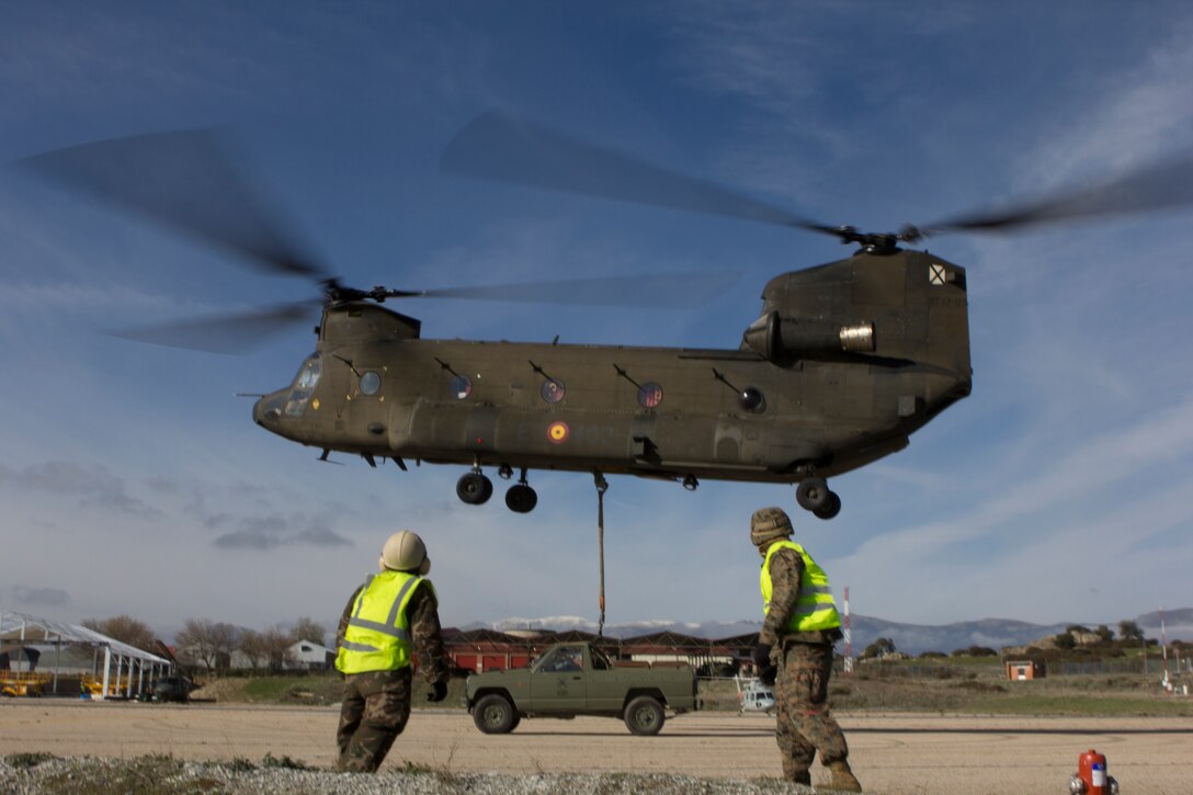 A U.S. Marine with SPMAGTF Crisis Response - Africa and a Spanish soldier with Transport Helicopter Battalion 5, watch a Spanish Army CH-47 Chinook lift a truck that they had attached its bottom at Colmenar de Viejo, Spain, Nov. 18, 2014. The long distance transportation of vehicles by air can be used when conducting a disaster relief mission where vehicles are needed but key road and bridges are destroyed. The training conducted by the Marines and soldiers enhanced mission readiness and help build relationships between the two militaries. (U.S. Marine Corps photo by Cpl Jeraco Jenkins/Released).