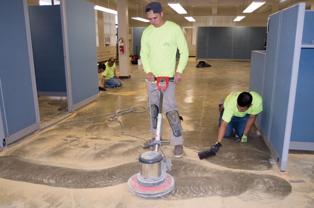 MARINE CORPS BASE HAWAII - Workers with Island Flooring of Oahu use a buffer to scrape remnants of carpet glue from the floor during the renovation of the Sports Medicine and Rehabilitation Therapy Center, Nov. 24, 2014. The center will re-open Dec. 3 with new vinyl composite tile and rubber matting to reduce physical stress on patients. (U.S. Marine Corps photo by Christine Cabalo)