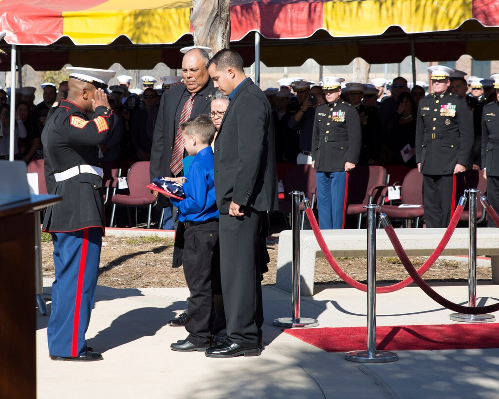 First Sgt. Alvoid Hamilton, first sergeant for 1st MSOB, presents a folded American Flag to the family of Staff Sgt. Christopher Diaz a Military Working Dog handler who was killed in action, Sept. 28, 2011, during a Navy Cross and Bronze Star awards ceremony aboard Camp Pendleton, Calif., Nov. 25, 2014.  (U.S. Marine Corps Photo by Sgt. Scott A. Achtemeier / Released)