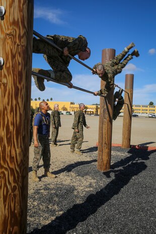 Recruits of Lima Company, 3rd Recruit Training Battalion, make their way over the double pull-up bar as Sgt. David Alvarado, drill instructor, ensures they use proper technique during the Obstacle Course II event aboard Marine Corps Recruit Depot San Diego, Nov. 20.  Drill instructors were stationed throughout the course to make sure proper safety and techniques were executed at each obstacle.