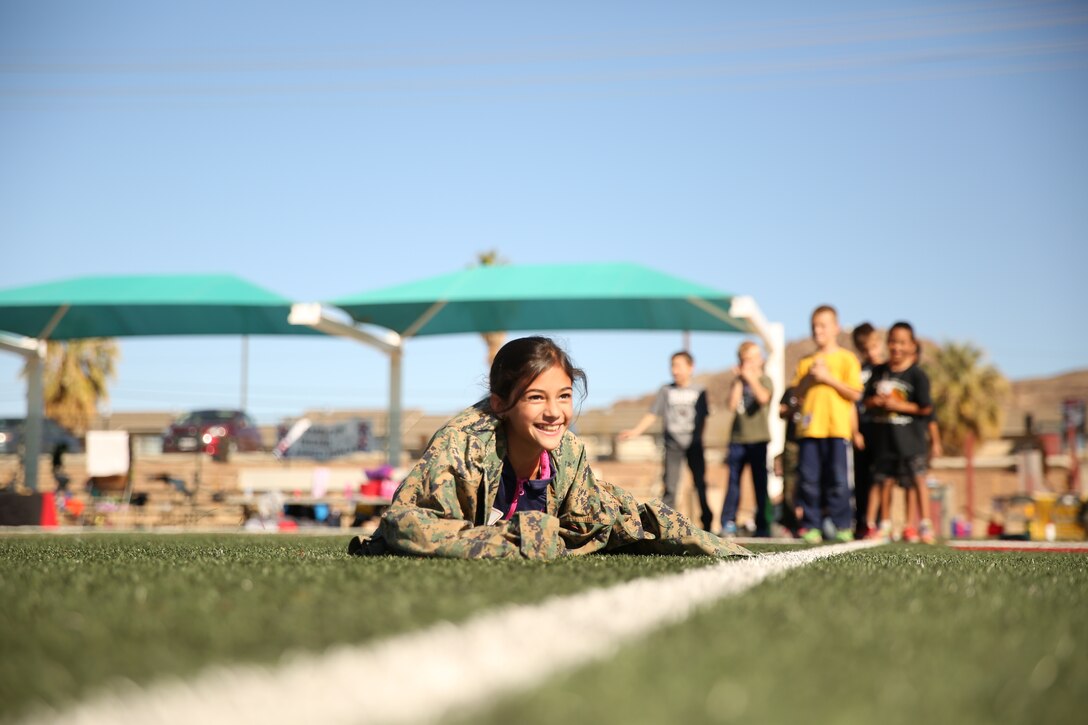 Sarah Benson, daughter of Ciara Benson, spouse, low crawls as part of a modified combat fitness test during the Lifestyle Insights Networking Knowledge Skills’ Combined Arms Exercise for Kids at Felix Field, Nov. 25, 2014. LINKS CAX for Kids gives military children a day-in-the-life perspective in order to see what their parents do. (Official Marine Corps Photo by Lance Cpl. Julio McGraw/Released)