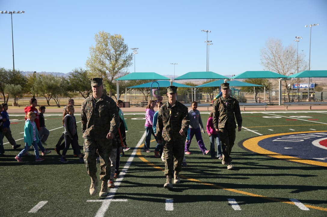 Marine Corps Communication-Electronics School students Pfc. Kyle Keith, Pfc. Jesse Straub and Pfc. Edward Hacker lead children during their lesson of close order drill at the Lifestyle Insights Networking Knowledge Skills Combined Arms Exercise for Kids at Felix Field, Nov. 25, 2014. Students from MCCES acted as squad leaders and answered questions the children had throughout the day. (Official Marine Corps Photo by Lance Cpl. Julio McGraw/Released)