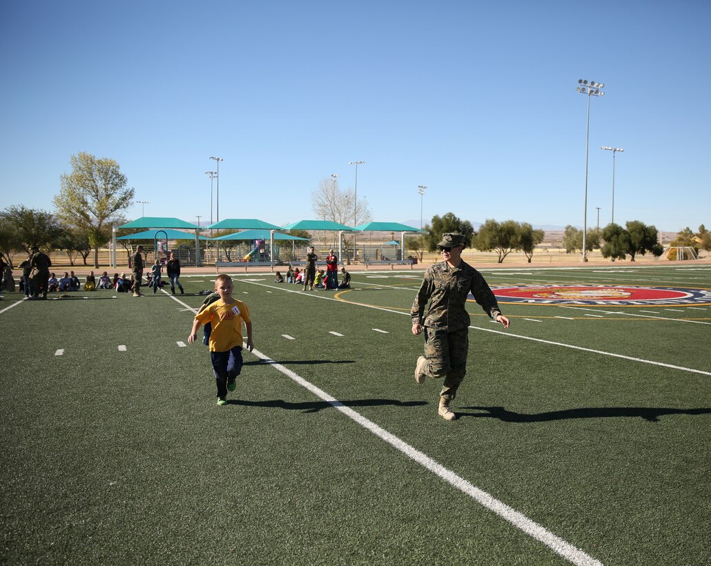 Cpl. Anna Steever, utilities technician, Marine Wing Support Squadron 374, cheers on children while they run a modified combat fitness test during the Lifestyle Insights Networking Knowledge Skills Combined Arms Exercise for Kids at Felix Field, Nov. 25, 2014. (Official Marine Corps Photo by Lance Cpl. Julio McGraw/Released)