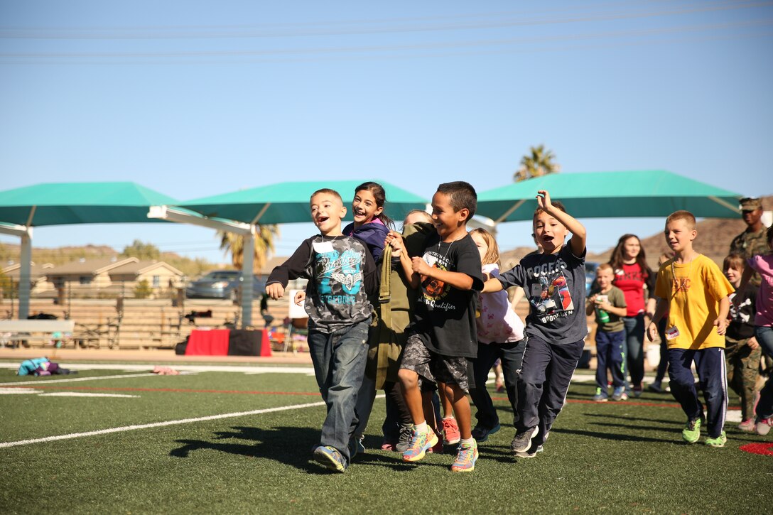 Combat Center children attempt to carry a sea bag filled with military gear across a football field during the Lifestyle Insights Networking Knowledge Skills’ Combined Arms Exercise for Kids at Felix Field, Nov. 25, 2014. The children were taught everything from rank structure to Marine Corps customs and courtesies. (Official Marine Corps Photo by Lance Cpl. Julio McGraw/Released)