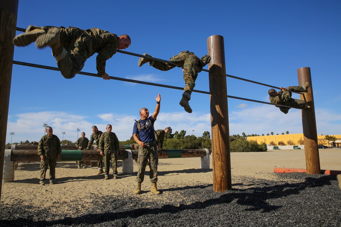 Recruits of Lima Company, 3rd Recruit Training Battalion, make their way over the double pull-up bar as Sgt. David Alvarado, drill instructor, ensures they use proper technique during the Obstacle Course II event aboard Marine Corps Recruit Depot San Diego, Nov. 20.  Drill instructors were stationed throughout the course to make sure proper safety and techniques were executed at each obstacle.
