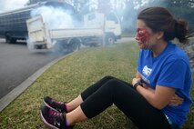 A victim of a simulated hazardous materials vehicle crash awaits emergency medical attention from 18th Civil Engineer Squadron firefighters as part of a mission focused exercise on Kadena Air Base, Japan, Dec. 2, 2014. During MFEs, wing inspection team members use special makeup on simulated casualties to provide realism to the different training scenarios. (U.S. Air Force photo by Senior Airman Maeson L. Elleman/Released) 