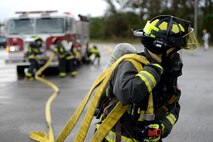 A Kadena firefighter from the 18th Civil Engineer Squadron drags a fire hose during a simulated burning vehicle accident as part of a mission focused exercise on Kadena Air Base, Japan, Dec. 2, 2014. The MFE is designed to train Airmen on proper techniques and procedures for an array of scenarios from chemical attacks to mass casualties. (U.S. Air Force photo by Senior Airman Maeson L. Elleman/Released)