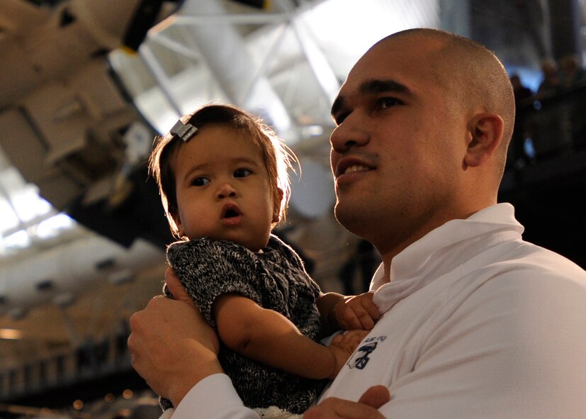 Capt. Gilberto Perez, White House Communications Agency network systems chief, and his daughter, watch a flash mob at the Smithsonian National Air and Space Museum Udvar-Hazy Center in Chantilly, Va., Dec. 2, 2014.  The United States Air Force Band played to spread the word about their free upcoming holiday concerts in the National Capital Region. Their mission is to honor those who have served, inspire American citizens to heightened patriotism and service, and positively impact the global community on behalf of the U.S. Air Force and America. (U.S. Air Force photo/ Senior Airman Nesha Humes)
