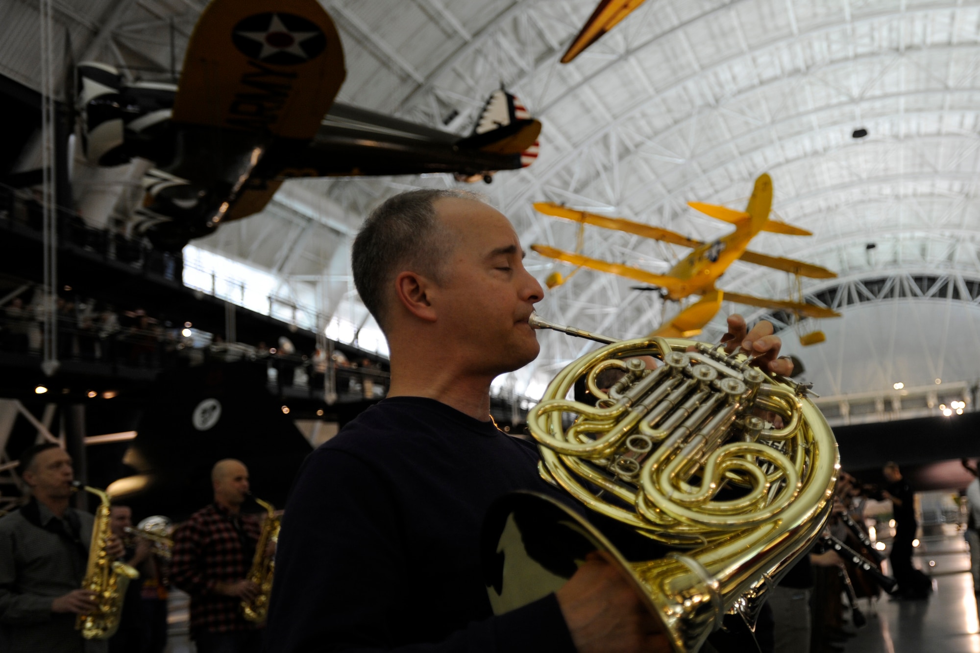 Senior Master Sgt. Phillip E. Krzywicki, United States Air Force Concert Band French hornist, plays during a flash mob at the Smithsonian National Air and Space Museum Udvar-Hazy Center in Chantilly, Va., Dec. 2, 2014.  The approximately six-minute flash-mob performance concluded with the playing of “Carol of the Bells” by Mykola Leontovych. (U.S. Air Force photo/ Senior Airman Nesha Humes)