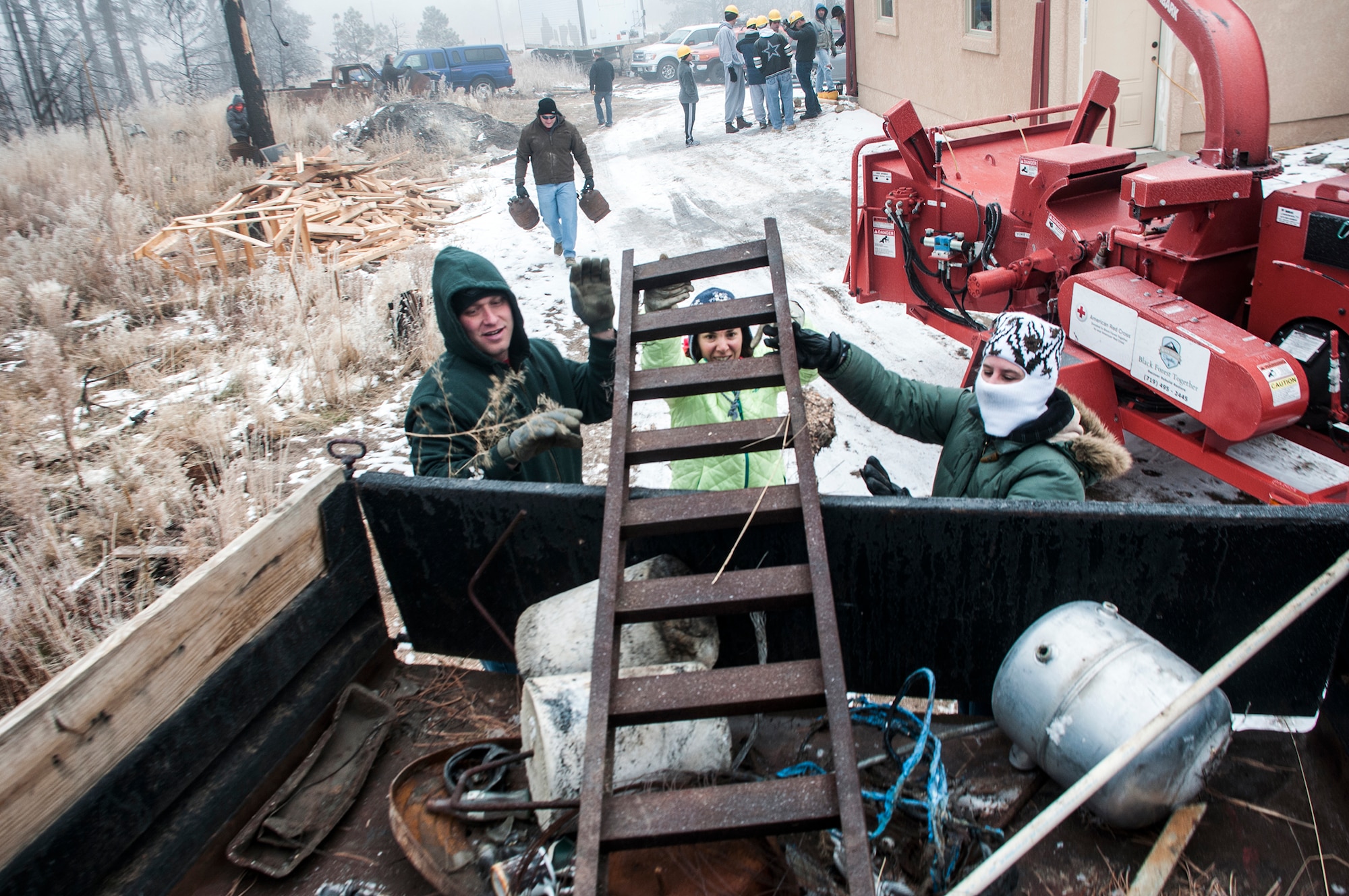 Airmen and family members with the 25th and 379th Space Range Squadrons volunteer their time and effort through Black Forest Together Nov. 26, 2014, at Black Forest, Colo. The volunteers dug a trench, built a fence, gathered burnt trees for a wood chipper and loaded damaged scrap metal into a dump truck. (U.S. Air Force photo/Staff Sgt. Julius Delos Reyes)