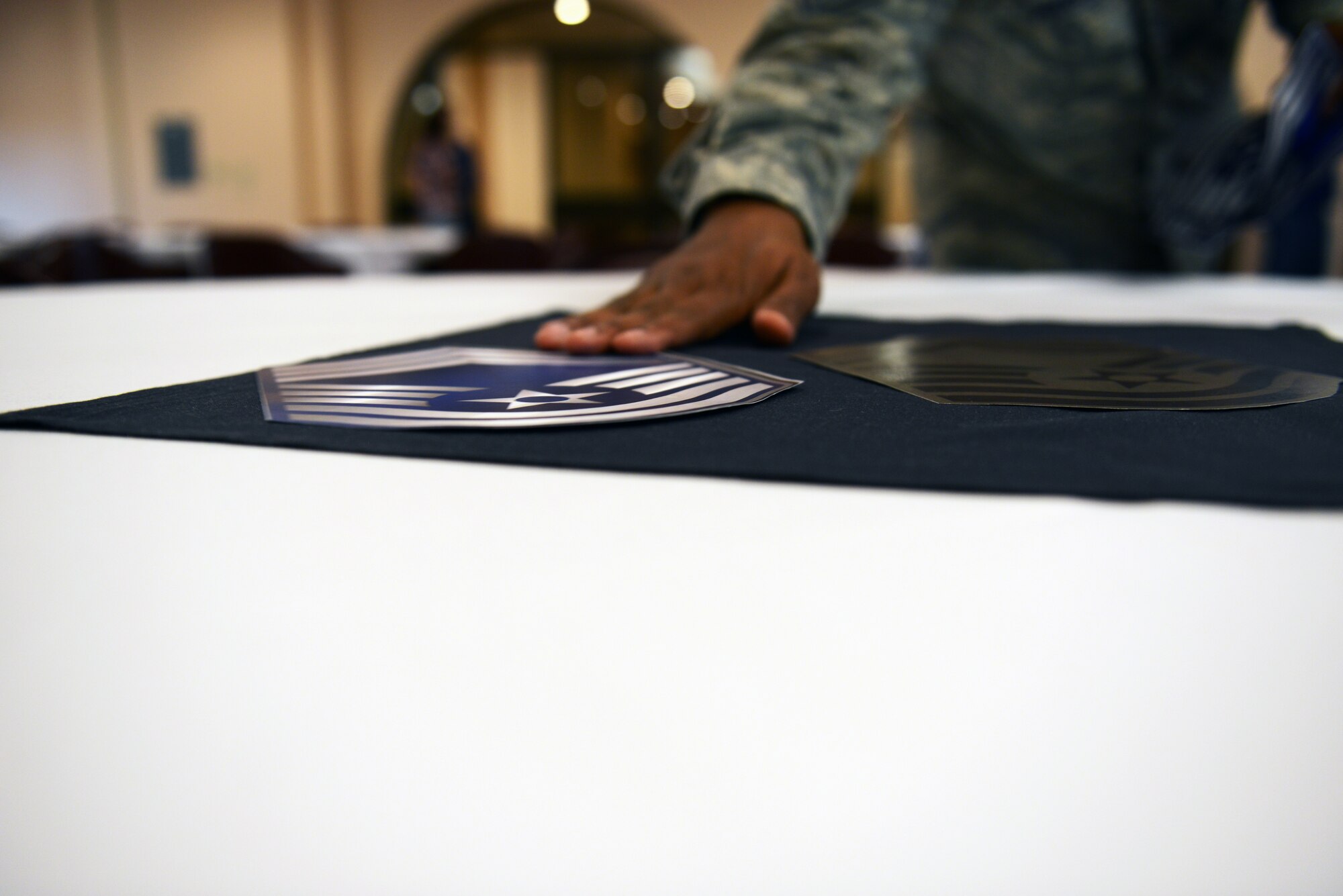 U.S. Chief Master Sgt. Derrick Harper, 7th Force Support Squadron superintendent, places a rank insignia on a table before the Dyess chief master sergeant promotion party Nov. 21, 2014, at Dyess Air Force Base, Texas. Six Dyess senior non-commissioned officers were selected to receive the highest enlisted rank. (U.S. Air Force photo by Airman 1st Class Kedesha Pennant/Released