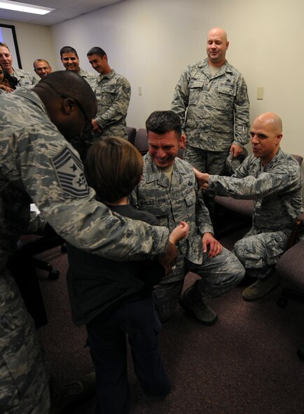 U.S. Air Force Senior Master Sgt. Antonio Goldstrom, 7th Communication Squadron superintendent, kneels so his son can assist Col. Michael Bob Starr, 7th Bomb Wing commander, in tapping on his new stripes Nov. 11, 2014, at Dyess Air Force Base, Texas. Goldstrom, who grew up in Las Vegas and has been in the Air force for 21 years, was selected for promotion to chief master sergeant after only his second time testing. (U.S. Air Force photo by Airman 1st Class Alexander Guerrero/Released)