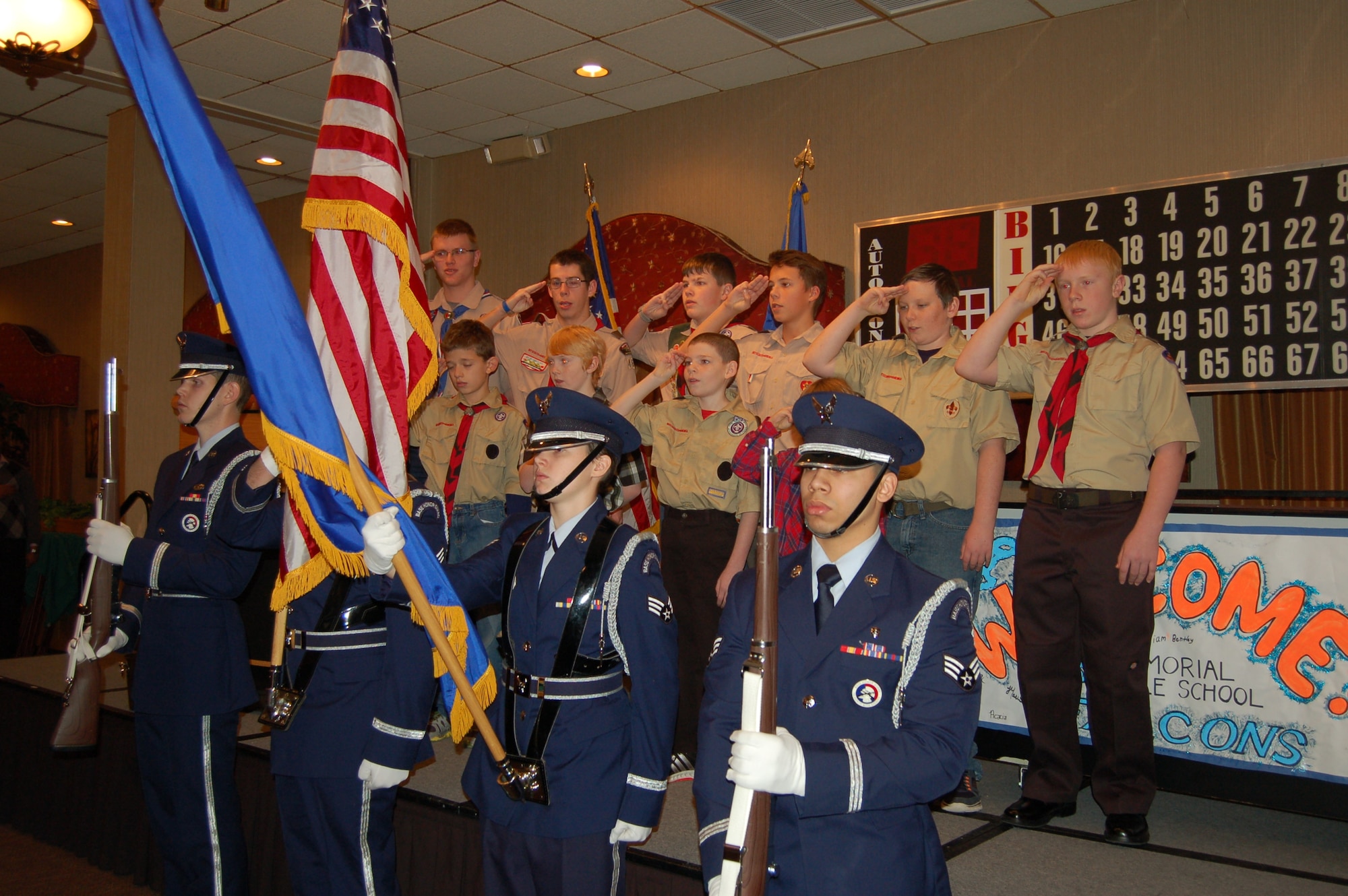 Minot’s Boy Scouts salute the colors presented by the Minot Air Force Base Honor Guard, at the Day of Love event on Minot AFB, N.D., Nov. 27, 2014. Children from the elementary school on base made a “Welcome” banner and cards for the event’s guests; the boy and girl scouts provided handmade ornaments as well as led the pledge of allegiance before the dinner and festivities. (Courtesy photo)