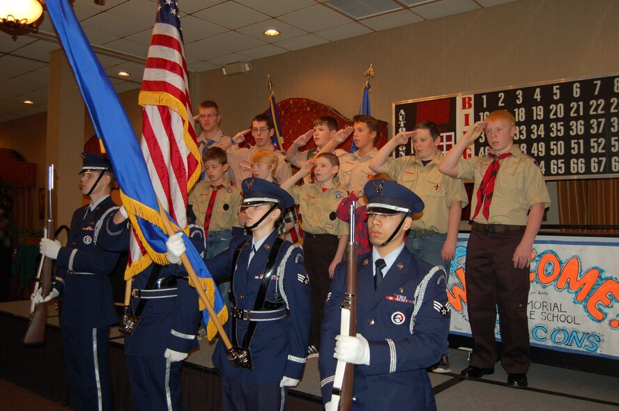 Minot’s Boy Scouts salute the colors presented by the Minot Air Force Base Honor Guard, at the Day of Love event on Minot AFB, N.D., Nov. 27, 2014. Children from the elementary school on base made a “Welcome” banner and cards for the event’s guests; the boy and girl scouts provided handmade ornaments as well as led the pledge of allegiance before the dinner and festivities. (Courtesy photo)