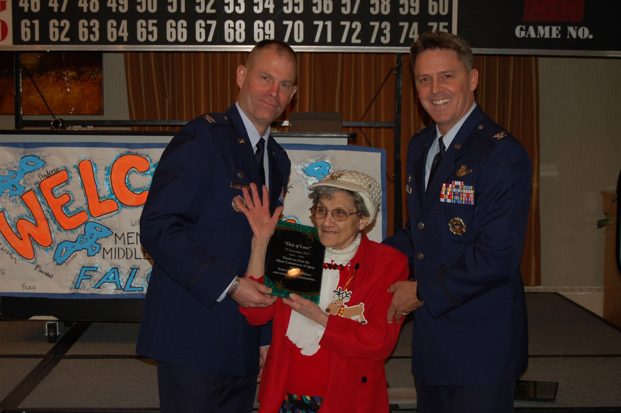 Ann Sellers, a guest at the Day of Love event, presents Col. Jason Armagost, 5th Bomb Wing commander, and Col. Mike Lutton, 91st Missile Wing commander, with a plaque on Minot Air Force Base, N.D., Nov. 27, 2014. The plaque was from the Minot Commission of Aging, Minot senior citizens and surrounding communities to thank Team Minot for welcoming them to the base for the holidays. The community was also presented a token of thanks from Team Minot for coming to the base. (Courtesy photo) 