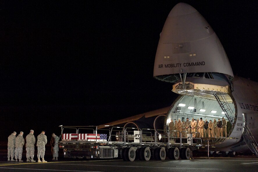 A C-5M Super Galaxy assigned to the 436th Airlift Wing, transported the remains of two fallen service members to Dover Air Force Base, Del., Nov. 26, 2014. Military members bow their heads at the forward loading ramp of the Super Galaxy at the beginning of a dignified transfer as a prayer is being read. On rare occasions, remains of fallen service members arrive at Dover AFB on C-5 aircraft prior to being transported to Air Force Mortuary Affairs Operations. (U.S. Air Force photo/Roland Balik)
