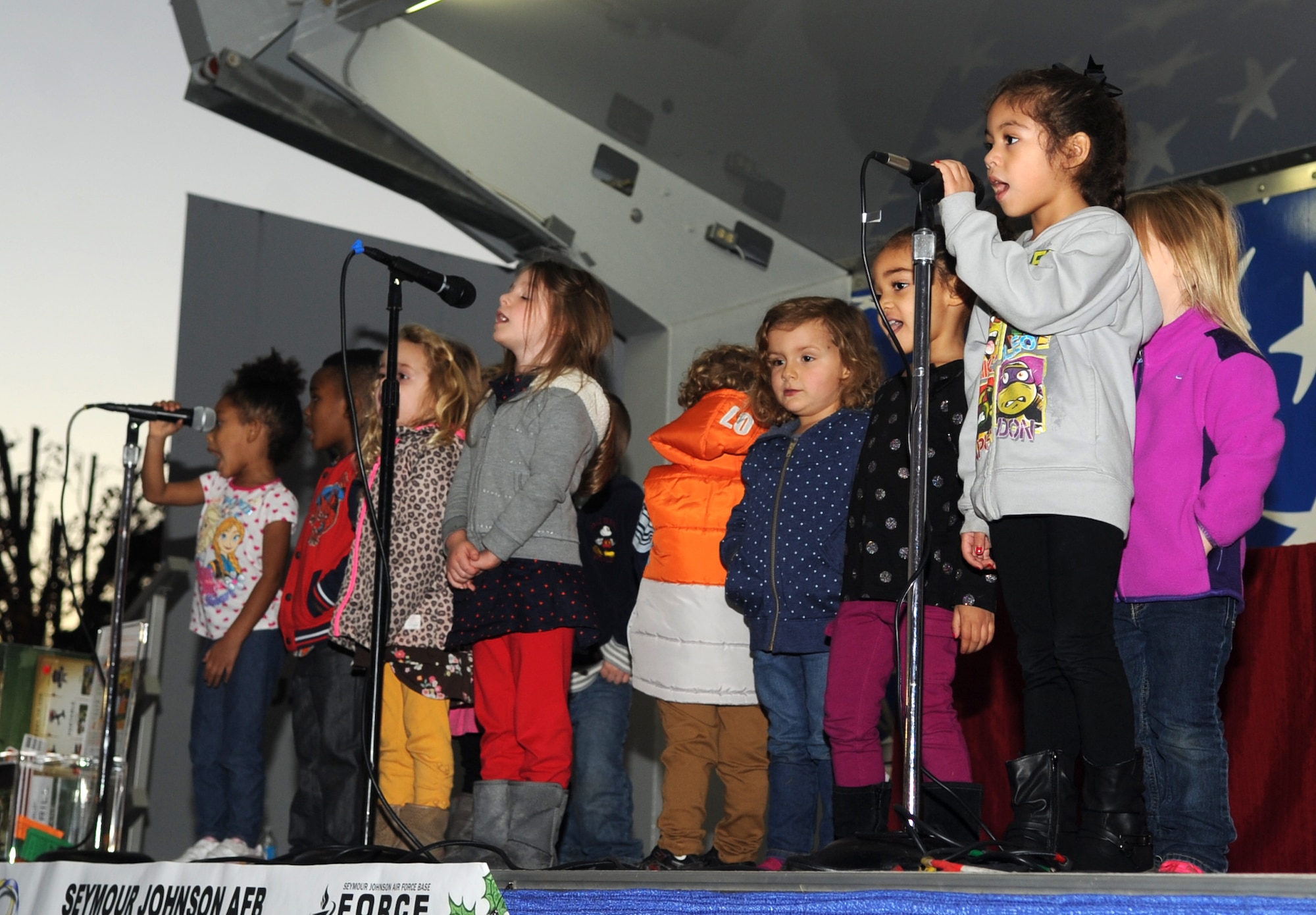 Children from the Child Development Center sing to their parents and onlookers during the base tree lighting ceremony at Seymour Johnson Air Force Base, North Carolina, Dec. 1, 2014. Different age groups from the CDC and the Youth Center delighted the audience with their rendition of holiday carols, including “What Does a Santa Say?” and “Rockin’ Around the Christmas Tree.” (U.S. Air Force photo/Senior Airman Ashley J. Thum)