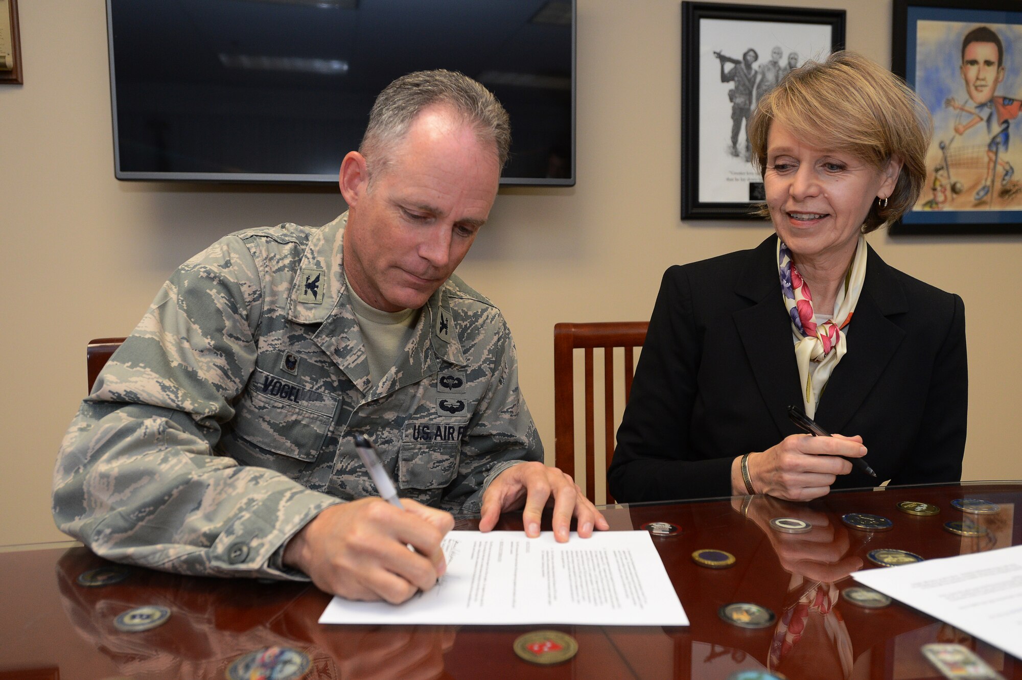 U.S. Air Force Col. Michael A. Vogel, 66th Air Base Group commander, signs a memorandum of understanding as Joanne Schoonover, dean of the capital and northeast region of Defense Acquisition University, watches during a signing ceremony on Hanscom Air Force Base, Mass., Dec. 1. The memorandum of understanding allows the university to operate on Hanscom. DAU, a Department of Defense institution, works to provide U.S. military and DOD civilian personnel access to the necessary training needed to produce a trained and efficient acquisition workforce.  (U.S. Air Force photo by Jerry Saslav)