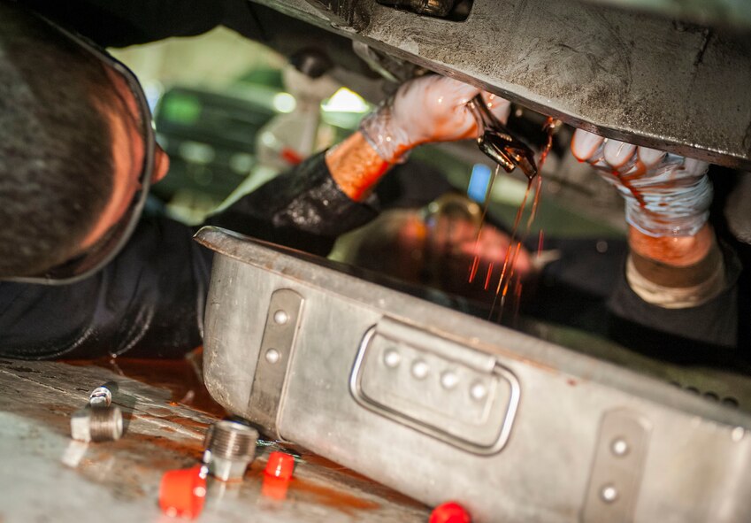 Senior Airman Michael Maldonada, 5th Maintenance Squadron air ground equipment journeyman, and Airman 1st Class Nathan Austin, 5th MXS AGE apprentice, work together to repair a brake line on Minot Air Force Base, N.D., Nov. 25, 2014. Maldonada and Austin adjusted the brake pedal and repaired the brake line after isolating a minor fluid leak. (U.S. Air Force photo/Senior Airman Stephanie Morris)