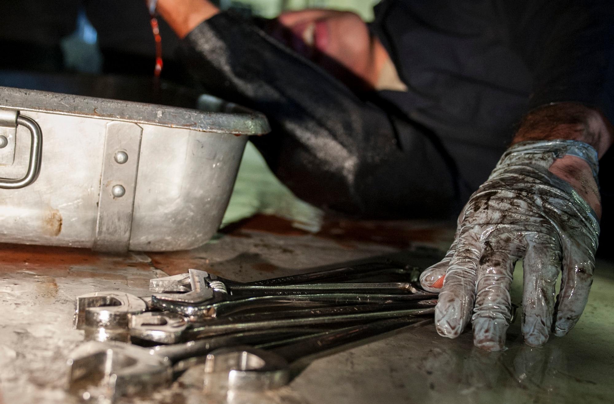 Senior Airman Michael Maldonada, 5th Maintenance Squadron air ground equipment journeyman, reaches for a wrench while repairing the brake line of a jammer on Minot Air Force Base, N.D., Nov. 25, 2014. Maldonada adjusted the brake pedal and repaired the brake line after isolating a minor fluid leak. (U.S. Air Force photo/Senior Airman Stephanie Morris)