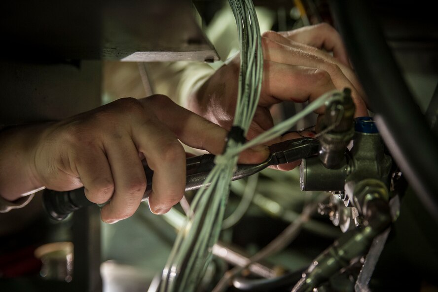 Senior Airman Jacob Jervell, 5th Maintenance Squadron air ground equipment journeyman, affixes safety wire to a cannon plug on a Dash 95 Air Source on Minot Air Force Base, N.D., Nov. 25, 2014. All parts not bolted in place on the air source must be held in place by safety wire. (U.S. Air Force photo/Senior Airman Stephanie Morris)