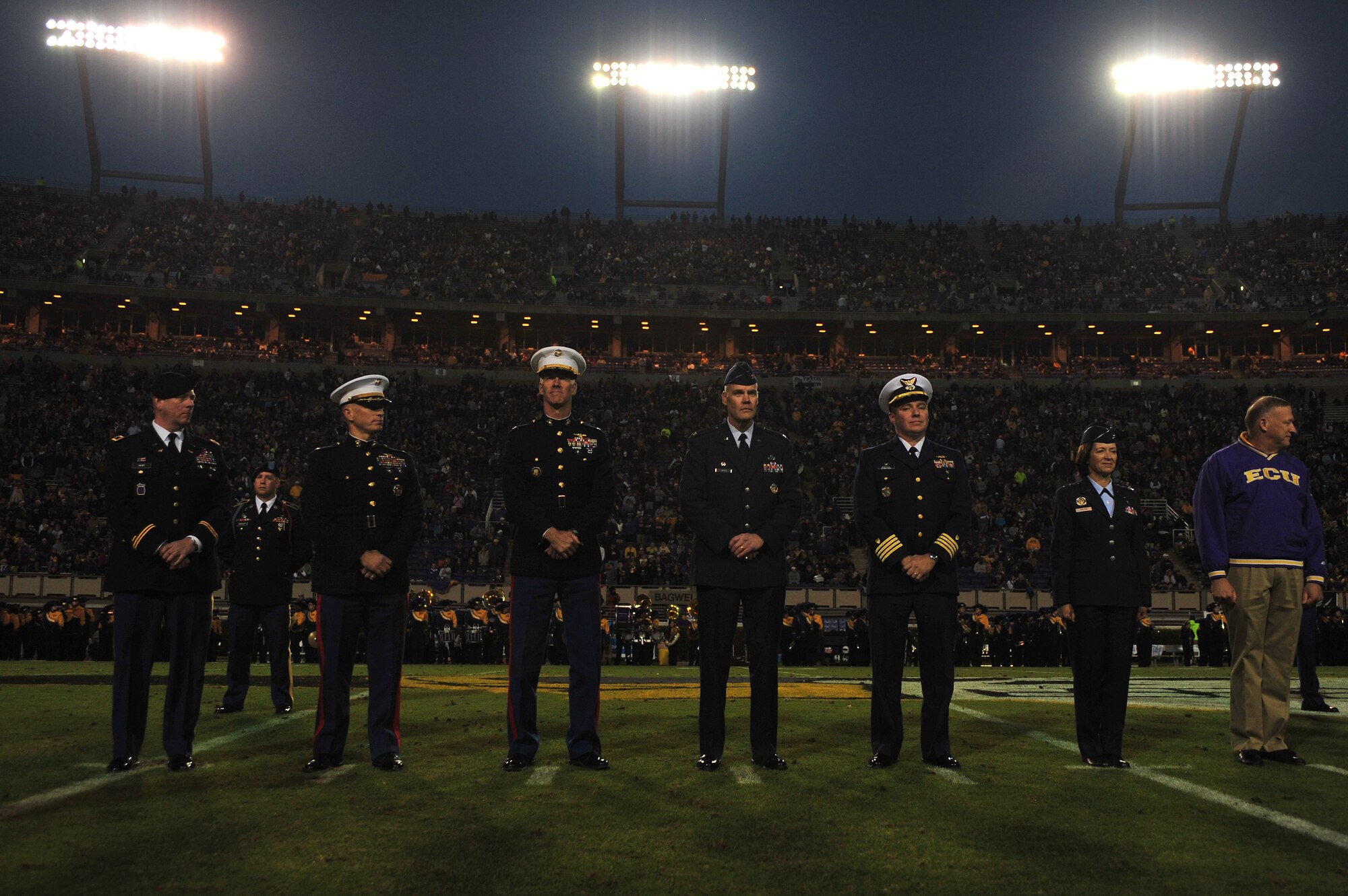 Service members stand at midfield during East Carolina University’s military appreciation day at Dowdy-Ficklen Stadium in Greenville, North Carolina, Nov. 22, 2014. Dr. Steve Ballard, East Carolina University chancellor, presented a coin to Col. Darrell Steele (center), 4th Maintenance Group commander, during the halftime ceremony. Ballard offered a commemorative coin in appreciation for those serving in the armed forces. (U.S. Air Force photo/Senior Airman John Nieves Camacho)
