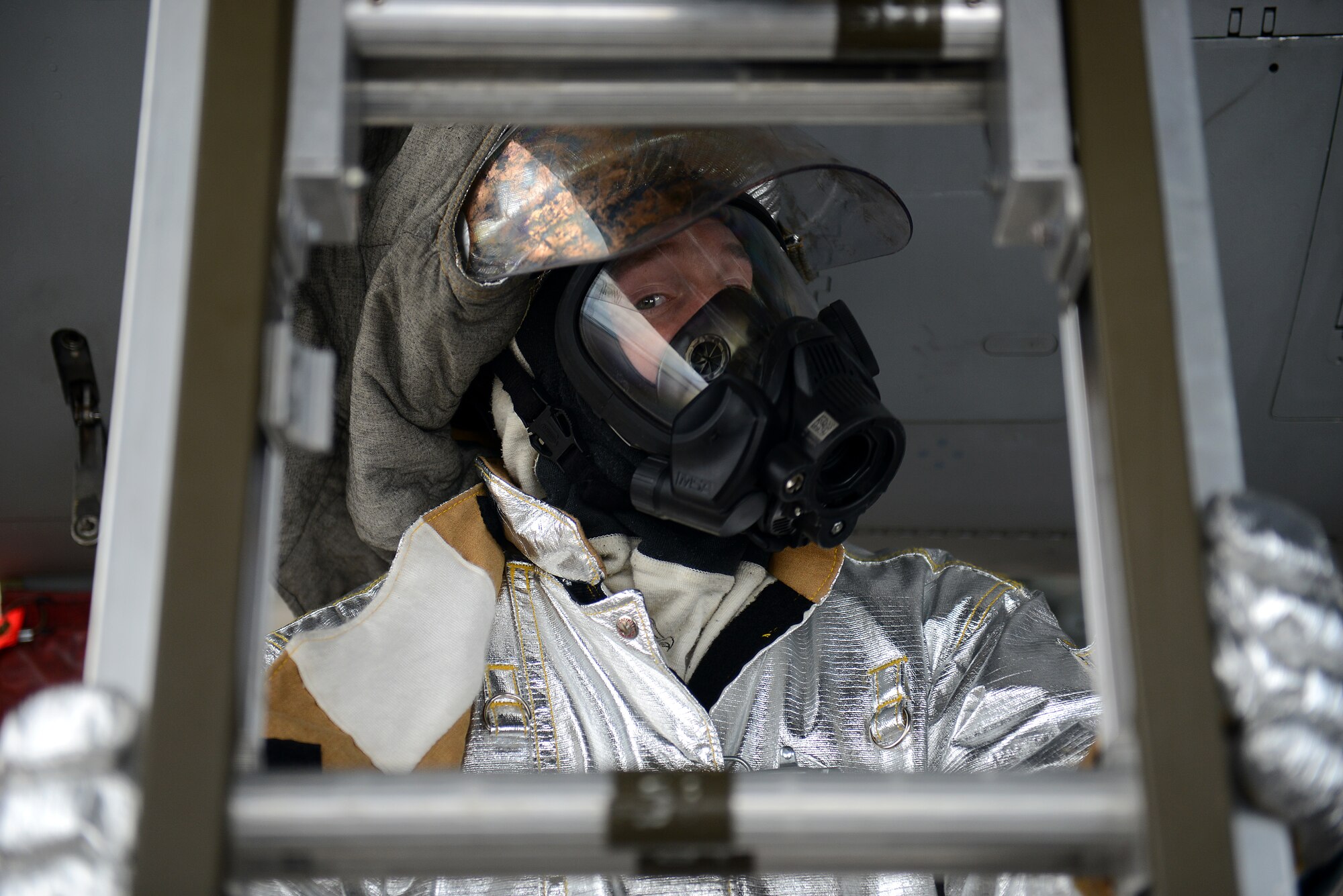 A firefighter with the 18th Civil Engineer Squadron supports a ladder so fellow firefighters can save a victim caught in an F-15C Eagle cockpit during a simulated aircraft fire as part of a mission focused exercise on Kadena Air Base, Japan, Dec. 1, 2014. Kadena periodically holds MFEs to train Airmen on a variety of scenarios ranging from active shooters to aircraft mishaps in order to prepare them for potential real-world situations in the future. (U.S. Air Force photo by Senior Airman Maeson L. Elleman/Released) 