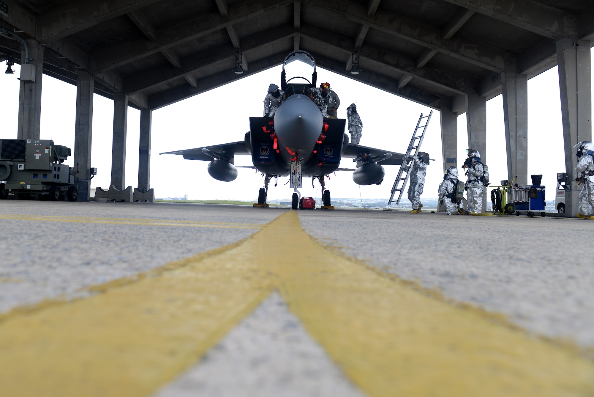 U.S. Air Force firefighters from the 18th Civil Engineer Squadron attempt to save a victim caught in the cockpit of an F-15C Eagle during a simulated aircraft fire as part of a mission focused exercise on Kadena Air Base, Japan, Dec. 1, 2014. The scenario was implemented to test Kadena's emergency responders on tactics and procedures in order to prepare them for potential real-world situations. (U.S. Air Force photo by Senior Airman Maeson L. Elleman/Released) 