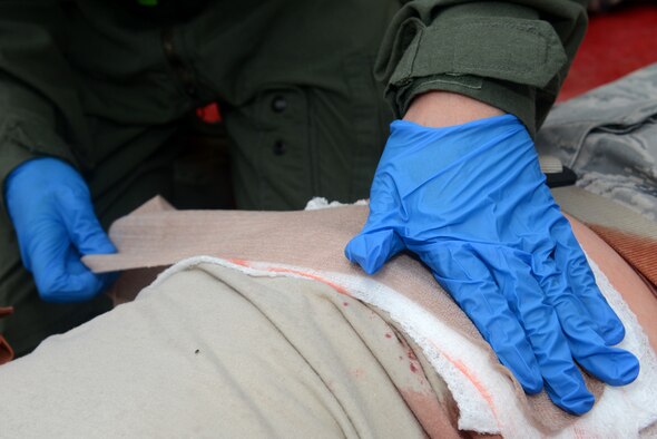 U.S. Air Force Captain Crystal Lenz, 18th Aerospace Medicine Squadron flight surgeon, wraps bandages on the wounds of a victim during a simulated active shooter scenario on Kadena Air Base, Japan, Dec. 1, 2014. The active shooter exercise was one of many situations Airmen will be thrust into during the MFE, which is slated to run through Dec. 4. (U.S. Air Force photo by Senior Airman Maeson L. Elleman/Released) 