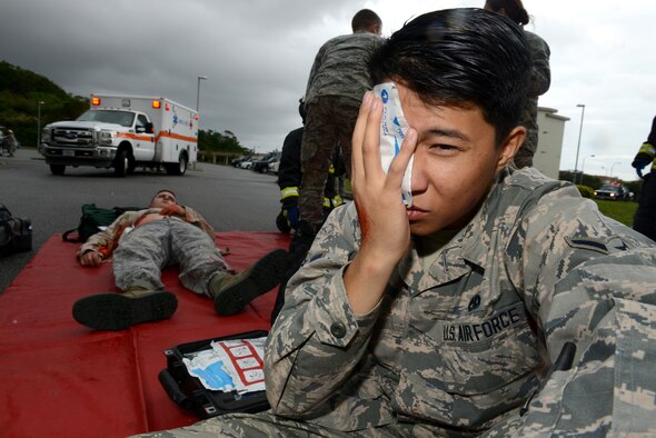 U.S. Air Force Airman Jim Uc, 718th Aircraft Maintenance Squadron electrical environmental systems technician, holds a bandage to his simulated eye wound during a simulated active shooter scenario on Kadena Air Base, Japan, Dec. 1, 2014. The scenario was implemented as part of a mission focused exercise, which is slated to run through Dec. 4. During the exercise, Airmen will be tested on a variety of scenarios ranging from self-aid and buddy care to chemical attacks. (U.S. Air Force photo by Senior Airman Maeson L. Elleman/Released)