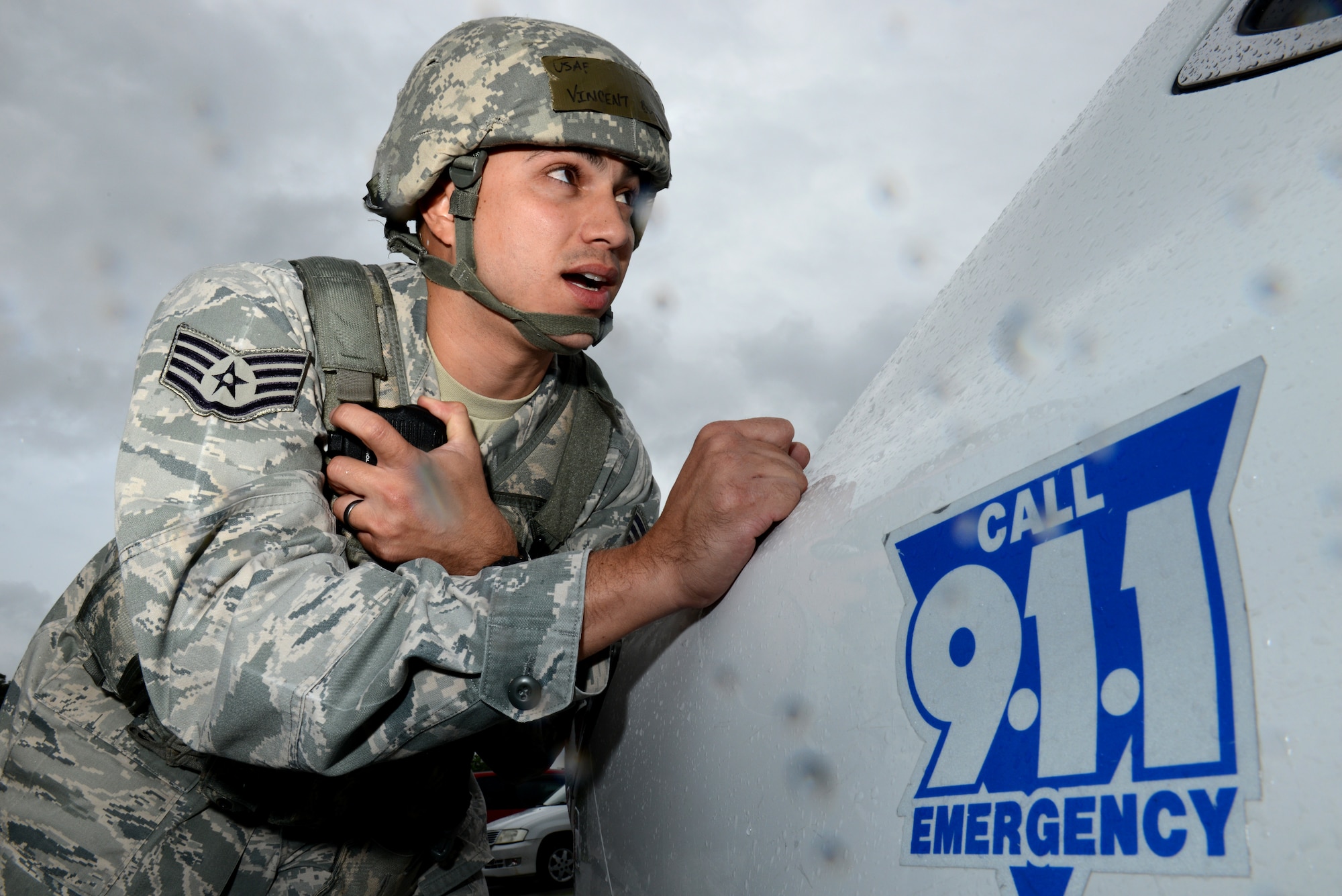 U.S. Air Force Staff Sgt. Vincent Bustillo, 18th Security Forces Squadron desk sergeant and initial entry team member, radios for support from behind a patrol vehicle during a simulated active shooter scenario on Kadena Air Base, Japan, Dec. 1, 2014. The scenario was implemented to test Kadena's emergency responders on tactics and procedures in order to prepare them for potential real-world situations. (U.S. Air Force photo by Senior Airman Maeson L. Elleman/Released)